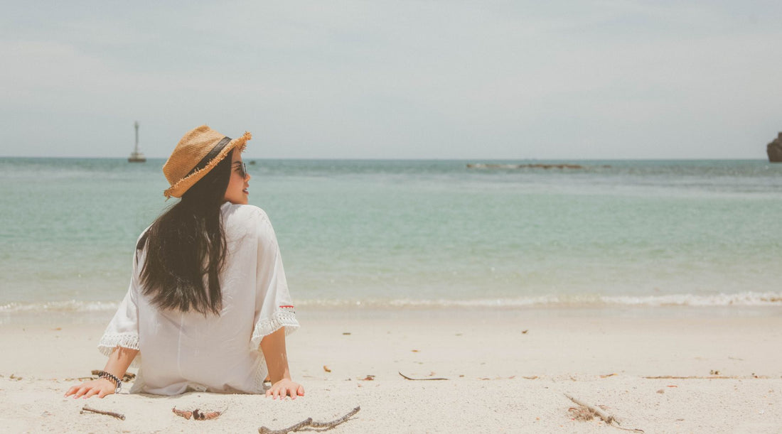 Frau mit Sonnenhut in Sommerhitze am Strand