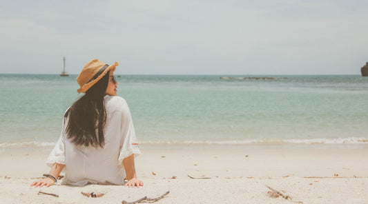 Frau mit Sonnenhut in Sommerhitze am Strand
